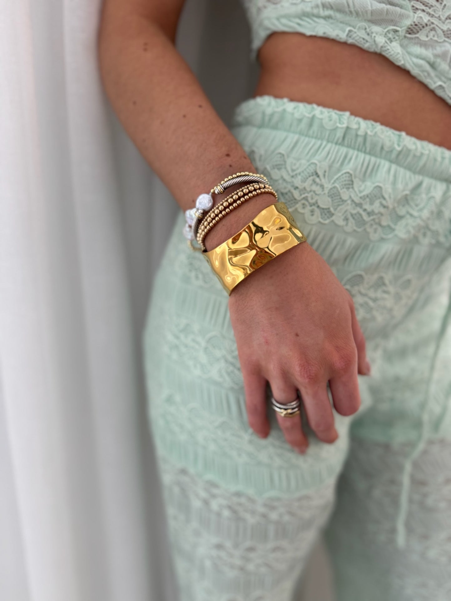woman styling a gold cuff bracelet with outfit