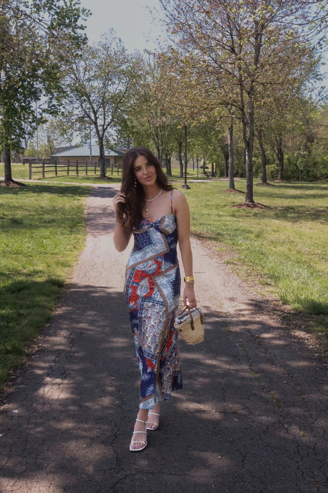 Woman wearing blue and red bandana patch midi dress with adjustable straps and open back and side slit.