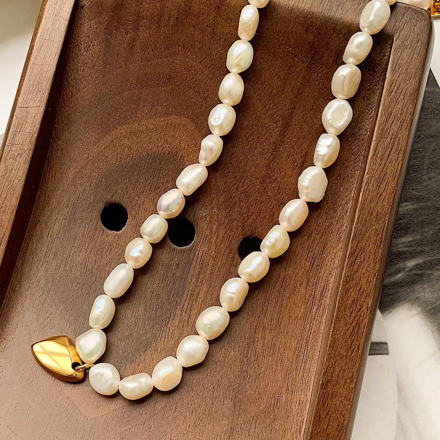 pearl beaded necklace with gold pendant on wooden display