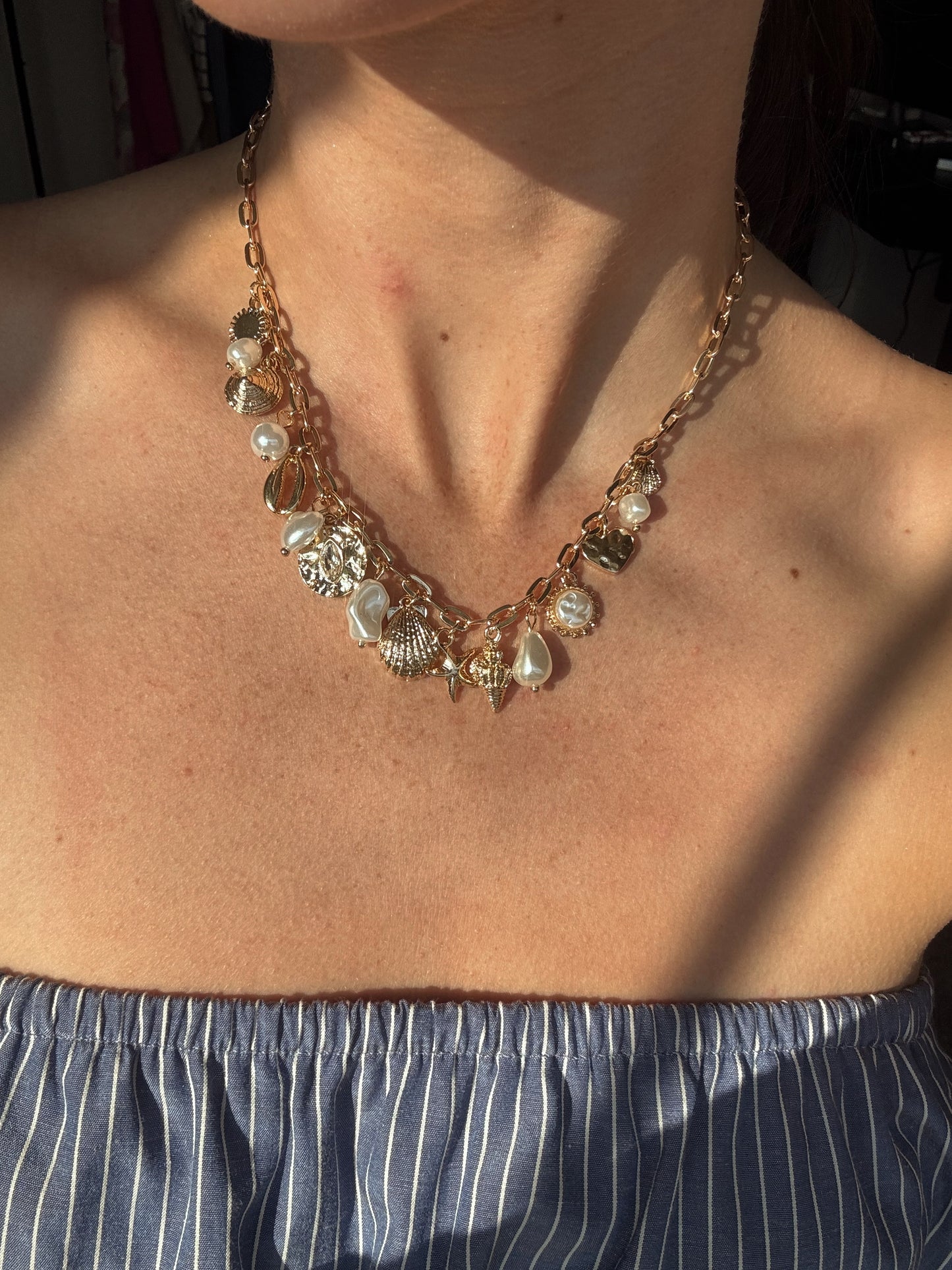Gold beach charm necklace with pearls and crystals being worn by someone
