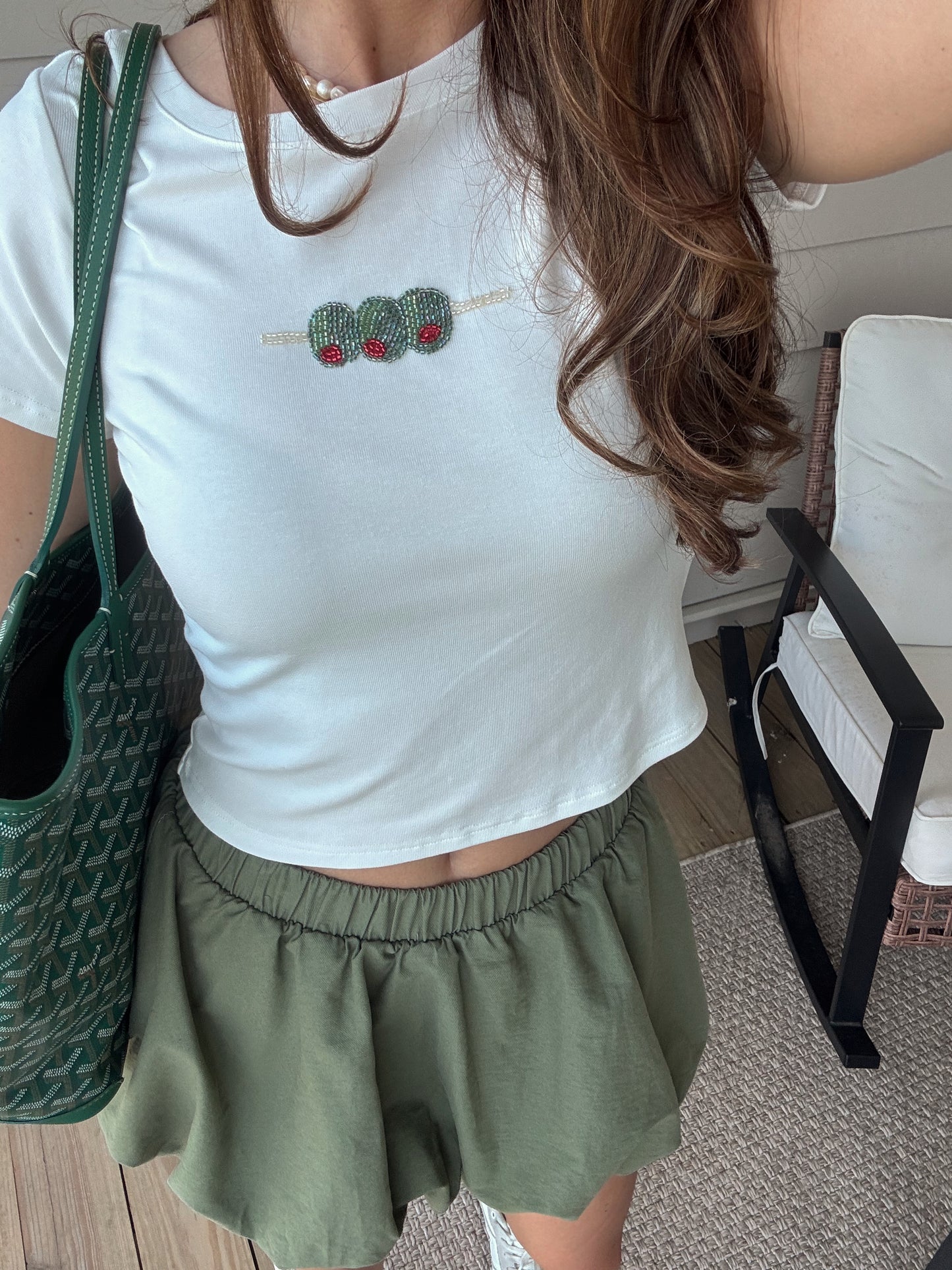 white tee with embroidered olives on it