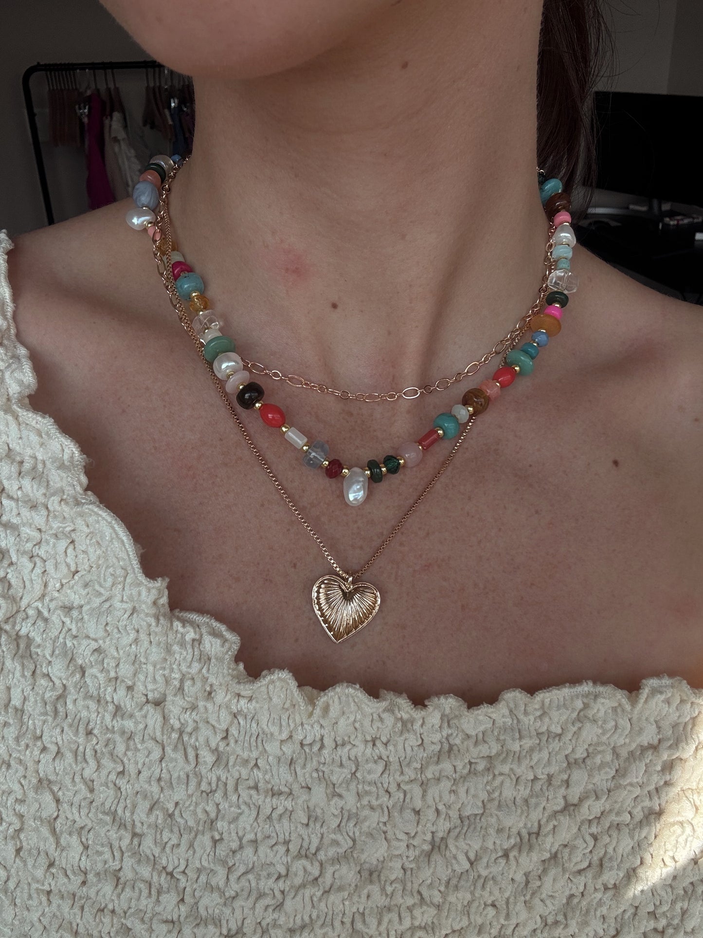 colorful beaded necklace stacked with gold heart pendant and chainlink 