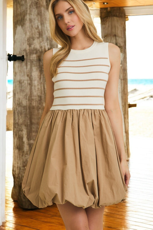 A woman wearing a beige and white striped sleeveless mini dress with a bubble hem.
