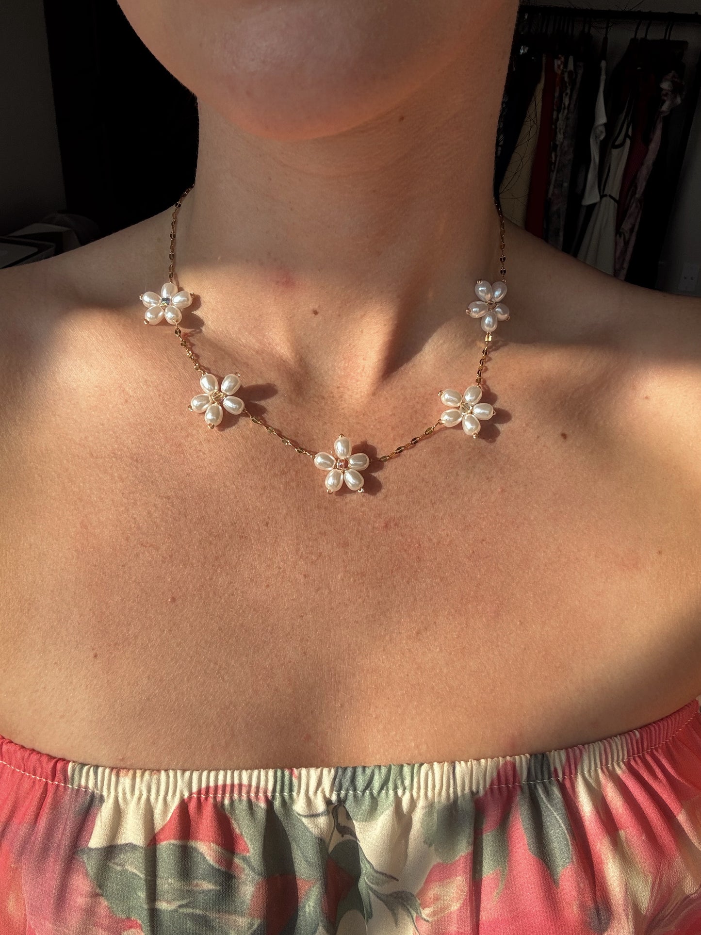 gold pearl flower necklace worn by someone 