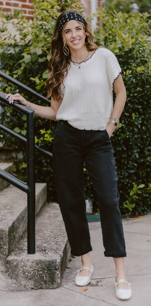 Woman wearing black barrel jeans and white knit tee