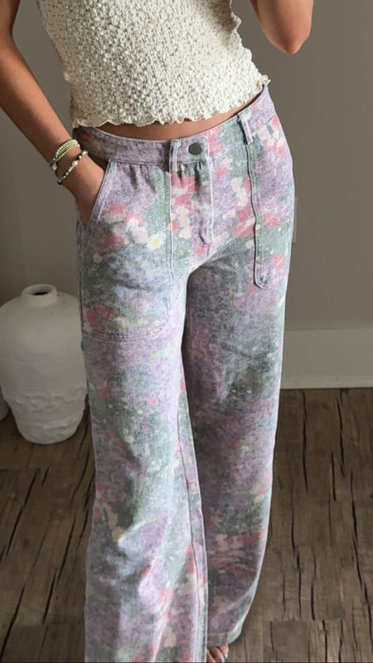 A pair of wide-leg floral pants in shades of pink and purple with a mid-rise waist and zipper closure.