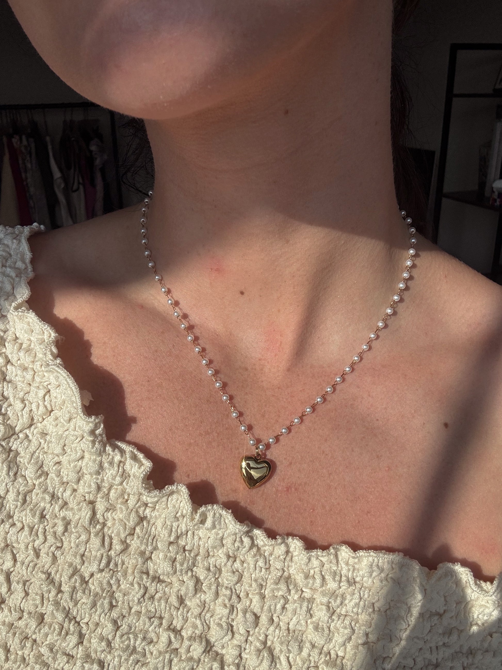 pearl studded Necklace with a heart pendant worn by a person, with a blurred background.