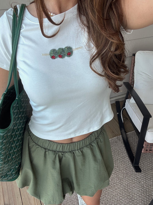 white tee with embroidered olives on it