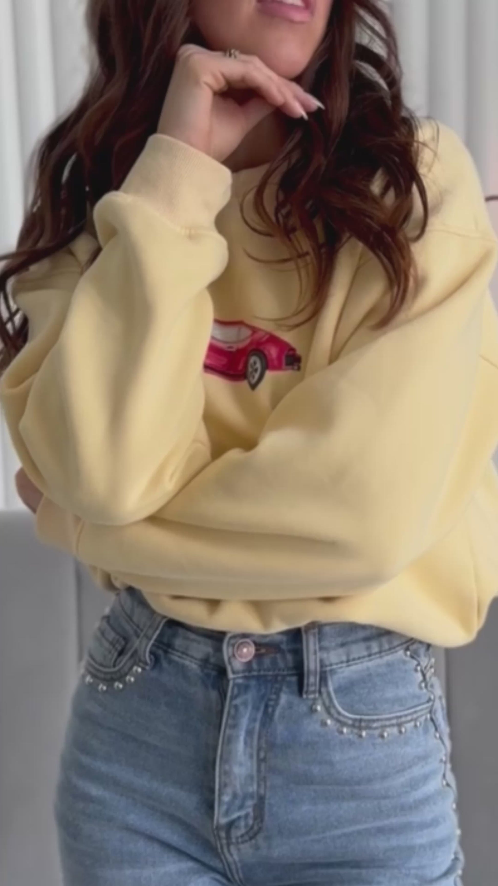 video of person wearing butter yellow crewneck sweater with vintage red car graphic on it