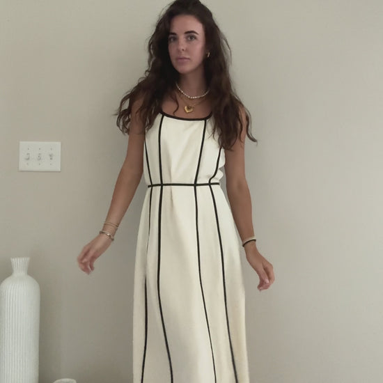 Video of someone wearing white midi dress with black stripes showing the tie waist and back of it.