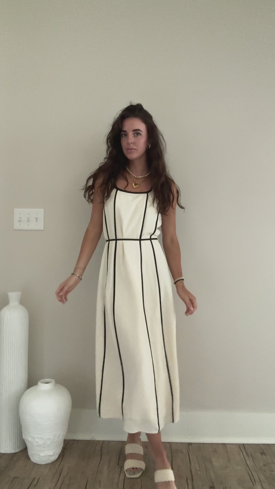 Video of someone wearing white midi dress with black stripes showing the tie waist and back of it.
